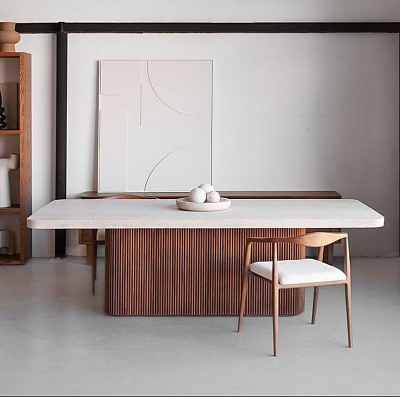 Table en travertin sur piètement en bois cannelé, dans une pièce épurée